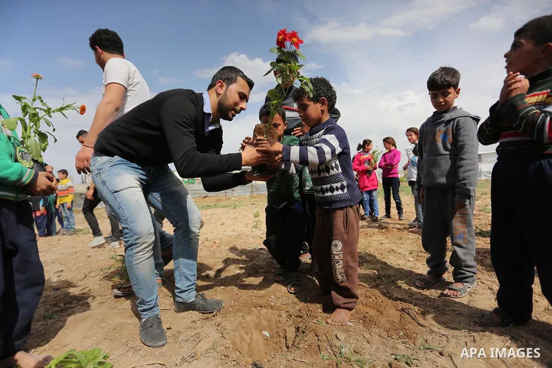 Palestinian children are grown roses during a rally demanding to reconstruction of their homes which destroyed during 2014 war in Shejaiya neighborhood in Gaza city, on March 24, 2016. Photo by Ashraf Amra