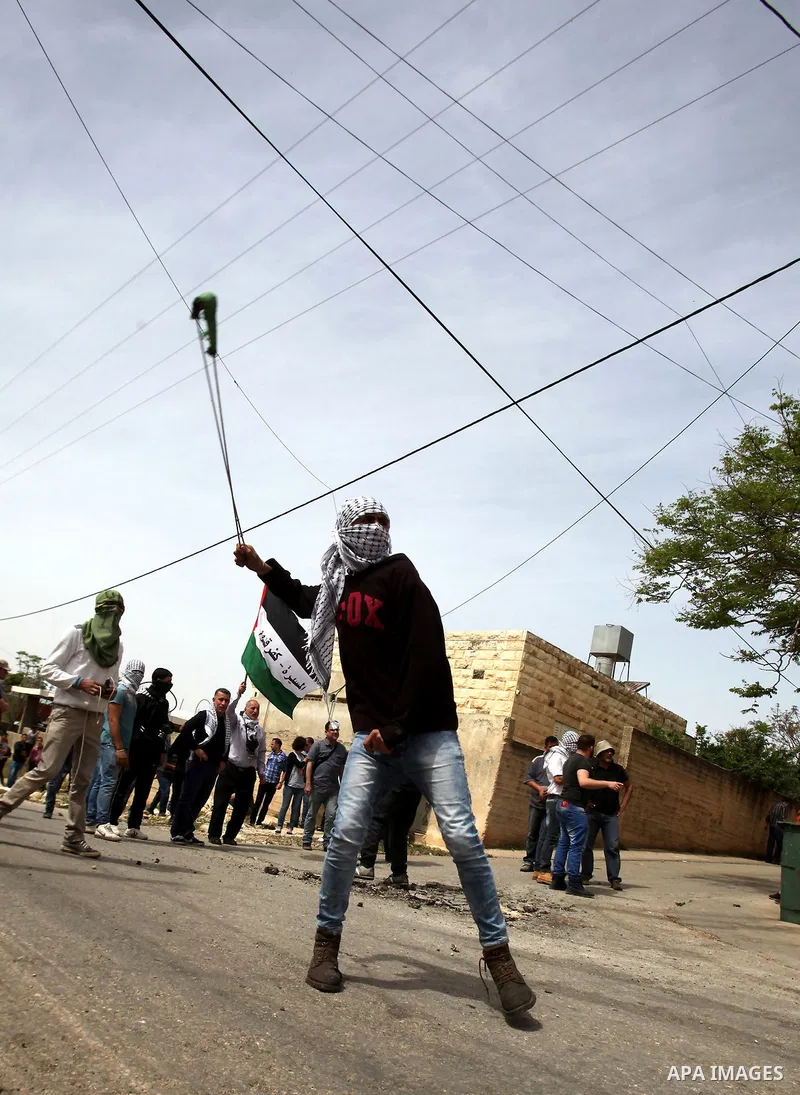 A Palestinian protester uses a slingshot to hurl stones toward Israeli security forces during clashes following a demonstration against the expropriation of Palestinian land by Israel in the village of Kfar Qaddum, near...