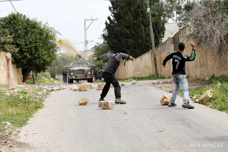 Palestinian protesters hurl stones toward An Israeli truck sprays foul smelling water during clashes with Israeli security forces following a demonstration against the expropriation of Palestinian land by Israel in the v...