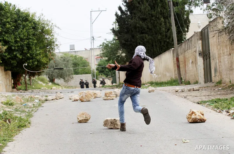 A Palestinian protester uses a slingshot to hurl stones toward Israeli security forces during clashes following a demonstration against the expropriation of Palestinian land by Israel in the village of Kfar Qaddum, near...