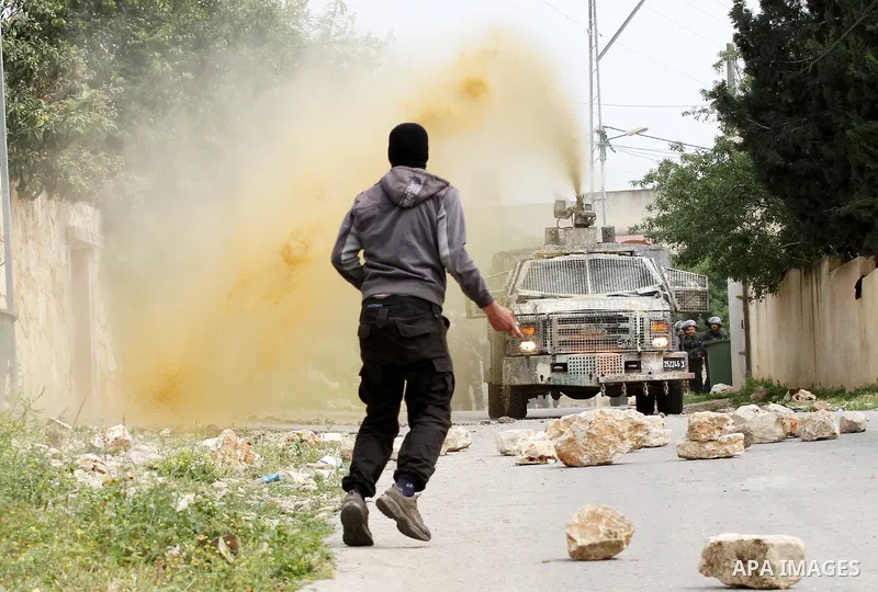 A Palestinian protester hurls stones toward An Israeli truck sprays foul smelling water during clashes with Israeli security forces following a demonstration against the expropriation of Palestinian land by Israel in the...