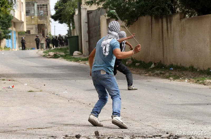 A Palestinian protester uses a slingshot to hurl stones toward Israeli security forces during clashes following a demonstration against the expropriation of Palestinian land by Israel in the village of Kfar Qaddum, near...