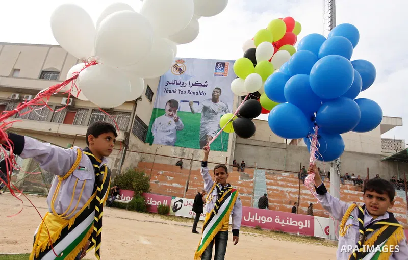 Palestinian chlidren hold ballons and posters bearing a portrait of Palestinian boy Ahmed Dawabsha, 5, who suffered severe burns in an arson attack by suspected Jewish attackers on his family home last July and in which...