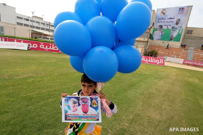 Palestinian chlidren hold ballons and posters bearing a portrait of Palestinian boy Ahmed Dawabsha, 5, who suffered severe burns in an arson attack by suspected Jewish attackers on his family home last July and in which...