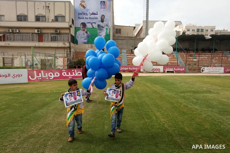 Palestinian chlidren hold ballons and posters bearing a portrait of Palestinian boy Ahmed Dawabsha, 5, who suffered severe burns in an arson attack by suspected Jewish attackers on his family home last July and in which...