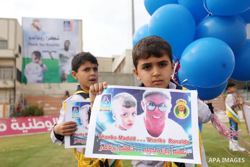 Palestinian chlidren hold ballons and posters bearing a portrait of Palestinian boy Ahmed Dawabsha, 5, who suffered severe burns in an arson attack by suspected Jewish attackers on his family home last July and in which...