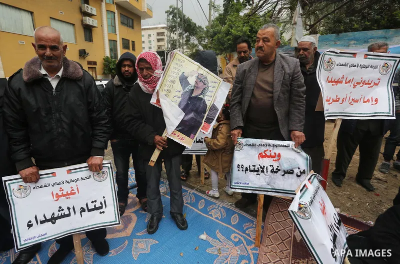 Palestinian families of martyrs, hold banners during a protest to demand their salaries, in front of Red cross office, in Gaza city, on March 28, 2016. Photo by Mohammed Asad