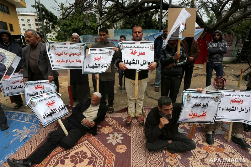 Palestinian families of martyrs, hold banners during a protest to demand their salaries, in front of Red cross office, in Gaza city, on March 28, 2016. Photo by Mohammed Asad