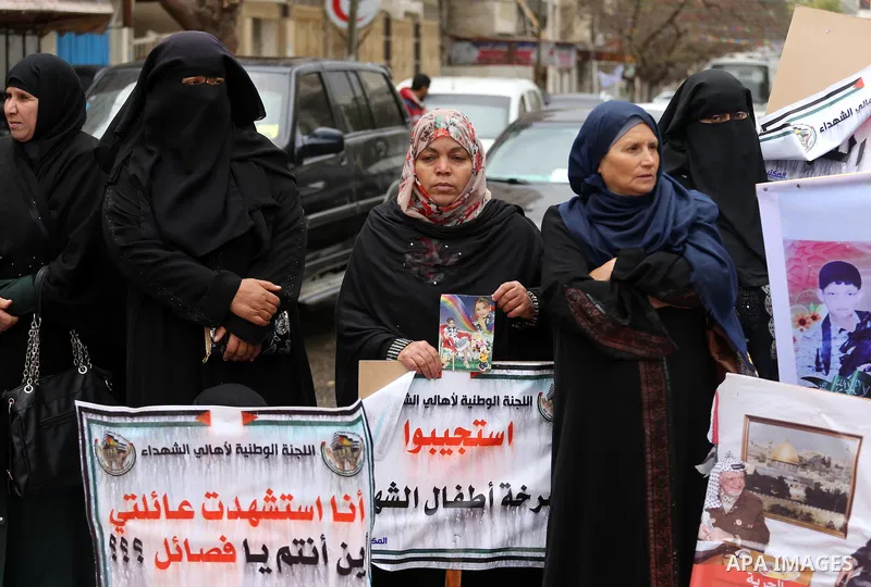 Palestinian families of martyrs, hold banners during a protest to demand their salaries, in front of Red cross office, in Gaza city, on March 28, 2016. Photo by Mohammed Asad