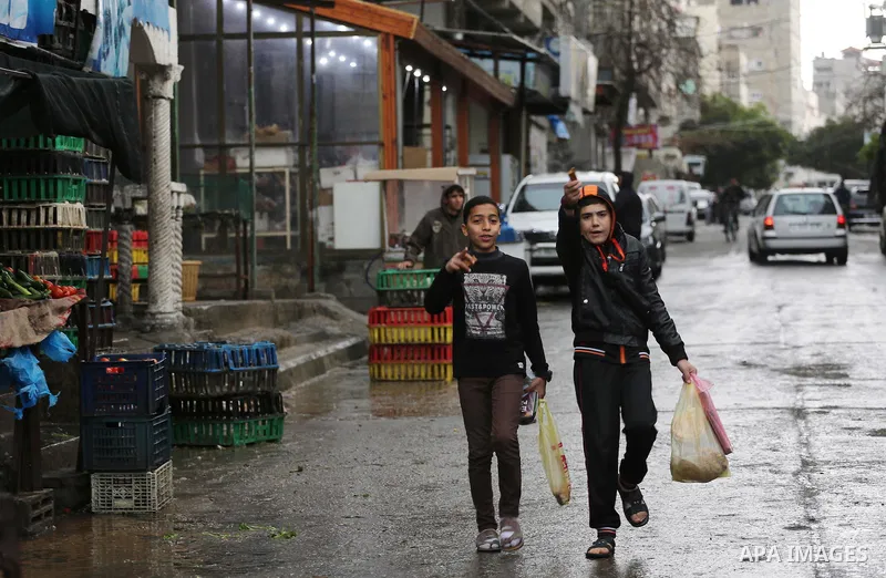 Palestinians walk in a flooded street during a rainy day, in Gaza city, on March 28, 2016. Photo by Mohammed Asad
