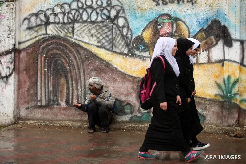 A Palestinian man begs at a street during a rainy day, in Khan Younis in the southern Gaza strip on March 28, 2016. Photo by Ashraf Amra