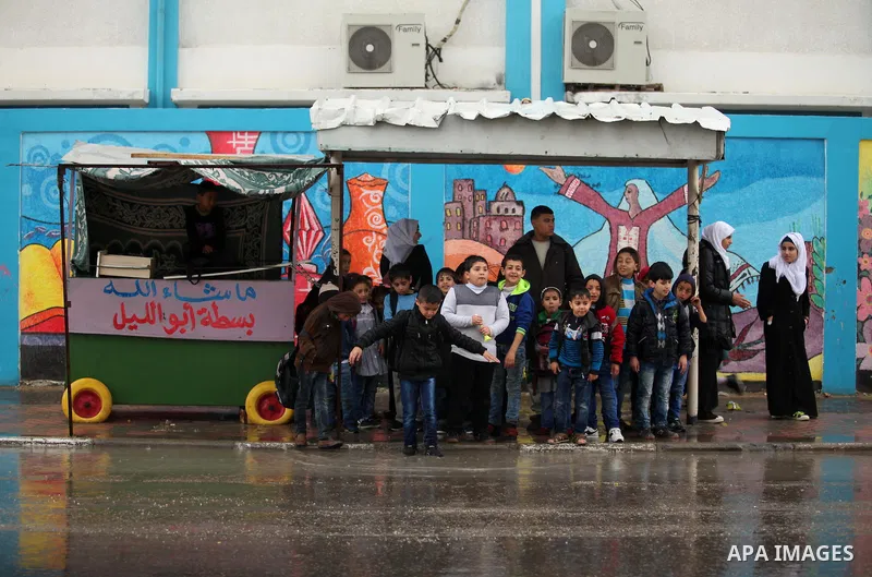 Palestinian students walk in a flooded street during a rainy day, in Khan Younis in the southern Gaza strip on March 28, 2016. Photo by Ashraf Amra