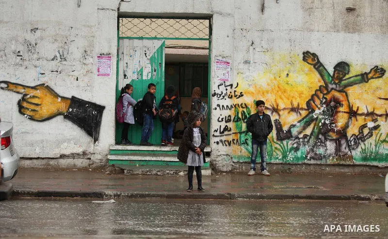 Palestinian students walk in a flooded street during a rainy day, in Khan Younis in the southern Gaza strip on March 28, 2016. Photo by Ashraf Amra