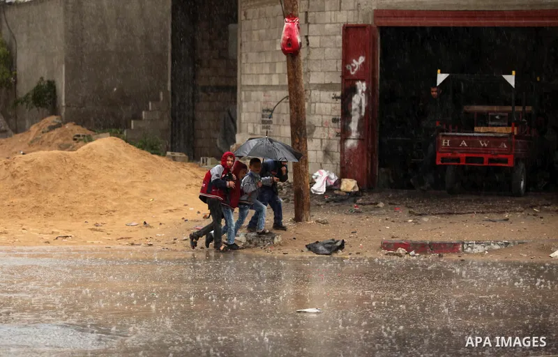 Palestinian students walk in a flooded street during a rainy day, in Khan Younis in the southern Gaza strip on March 28, 2016. Photo by Ashraf Amra