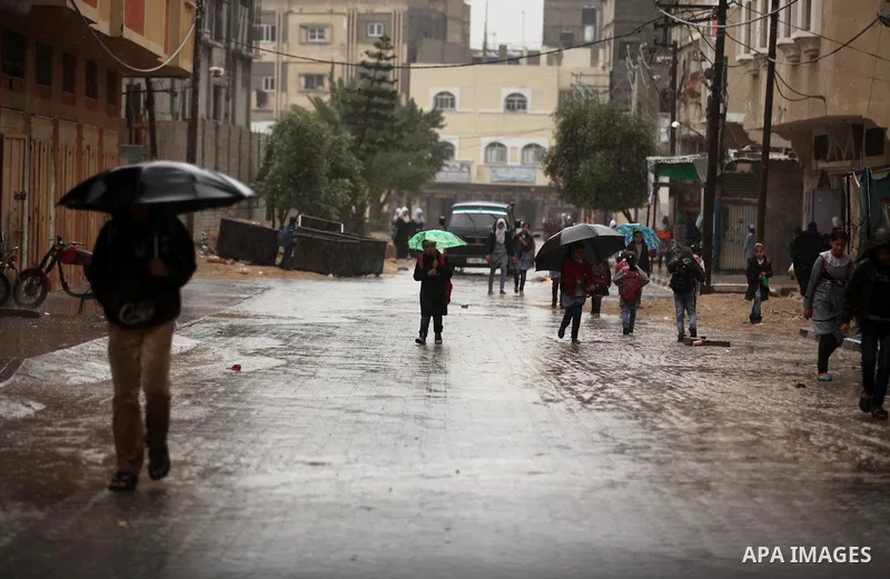 Palestinian students walk in a flooded street during a rainy day, in Khan Younis in the southern Gaza strip on March 28, 2016. Photo by Ashraf Amra