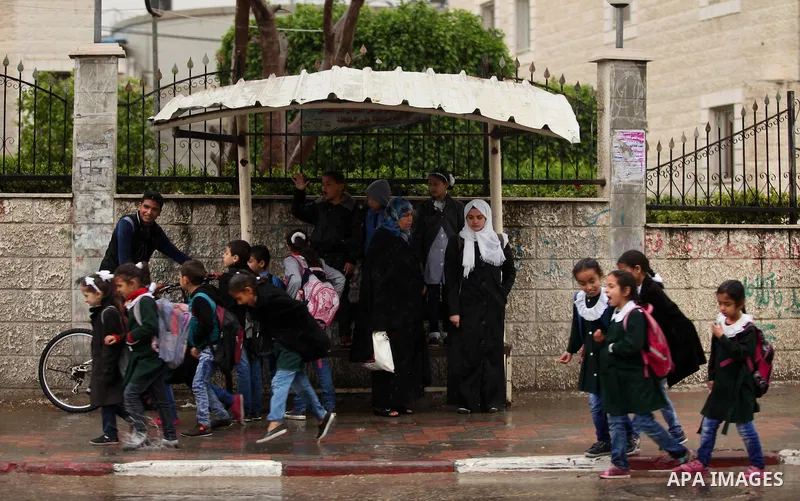 Palestinian students walk in a flooded street during a rainy day, in Khan Younis in the southern Gaza strip on March 28, 2016. Photo by Ashraf Amra