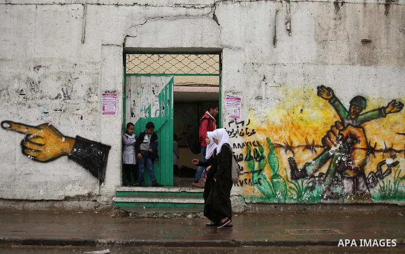 Palestinian students walk in a flooded street during a rainy day, in Khan Younis in the southern Gaza strip on March 28, 2016. Photo by Ashraf Amra