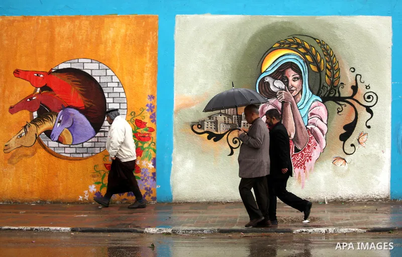 Palestinian students walk in a flooded street during a rainy day, in Khan Younis in the southern Gaza strip on March 28, 2016. Photo by Ashraf Amra