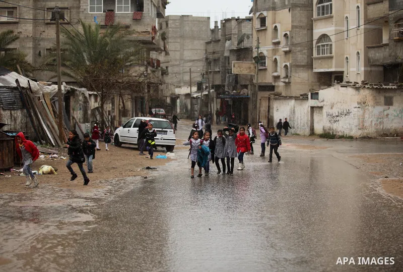 Palestinian students walk in a flooded street during a rainy day, in Khan Younis in the southern Gaza strip on March 28, 2016. Photo by Ashraf Amra