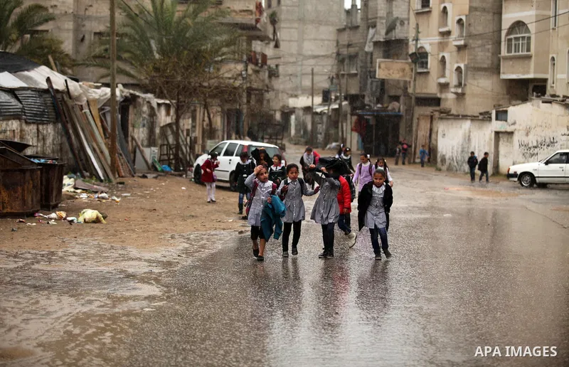 Palestinian students walk in a flooded street during a rainy day, in Khan Younis in the southern Gaza strip on March 28, 2016. Photo by Ashraf Amra