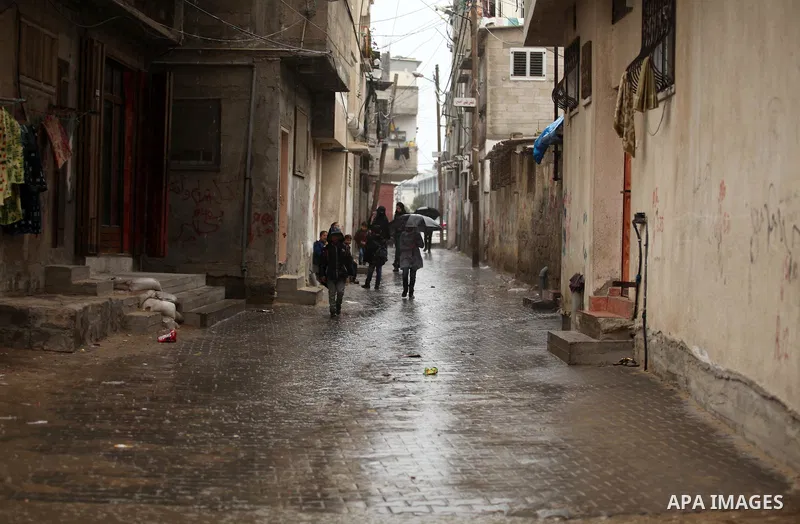 Palestinian students walk in a flooded street during a rainy day, in Khan Younis in the southern Gaza strip on March 28, 2016. Photo by Ashraf Amra