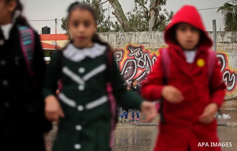Palestinian students walk in a flooded street during a rainy day, in Khan Younis in the southern Gaza strip on March 28, 2016. Photo by Ashraf Amra
