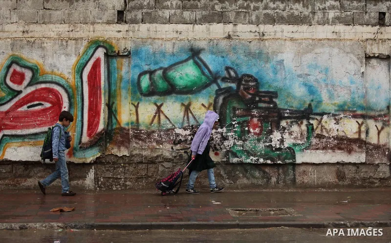 Palestinian students walk in a flooded street during a rainy day, in Khan Younis in the southern Gaza strip on March 28, 2016. Photo by Ashraf Amra
