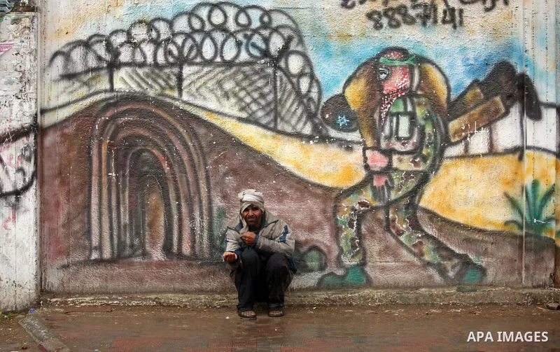 A Palestinian man begs at a street during a rainy day, in Khan Younis in the southern Gaza strip on March 28, 2016. Photo by Ashraf Amra