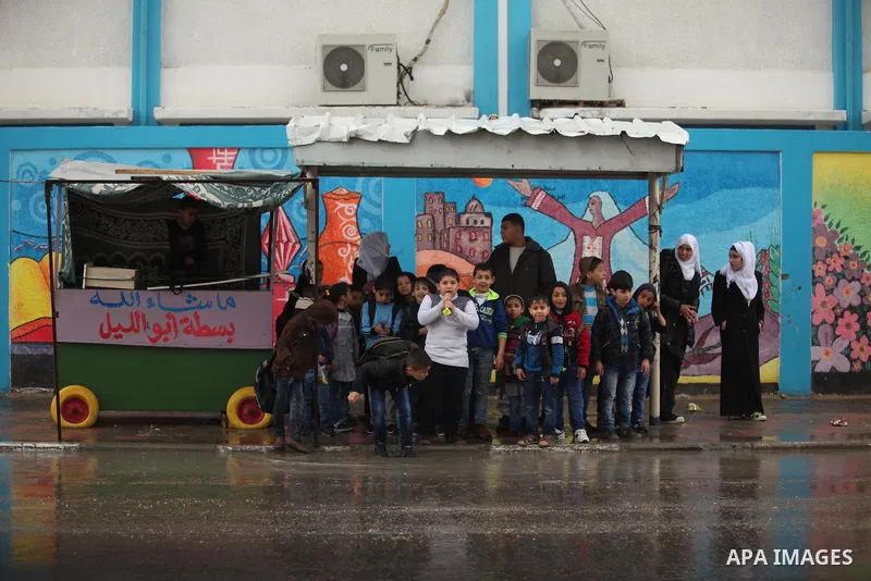 Palestinian students walk in a flooded street during a rainy day, in Khan Younis in the southern Gaza strip on March 28, 2016. Photo by Ashraf Amra