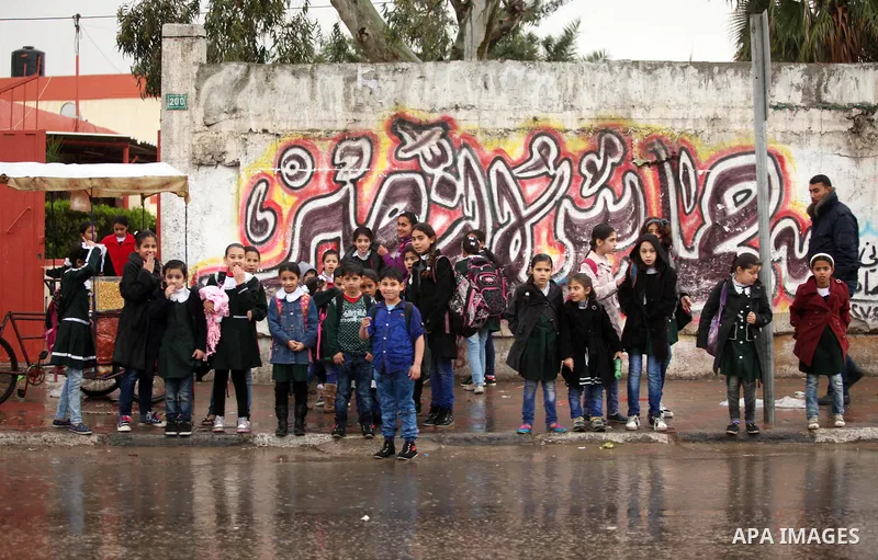 Palestinian students walk in a flooded street during a rainy day, in Khan Younis in the southern Gaza strip on March 28, 2016. Photo by Ashraf Amra