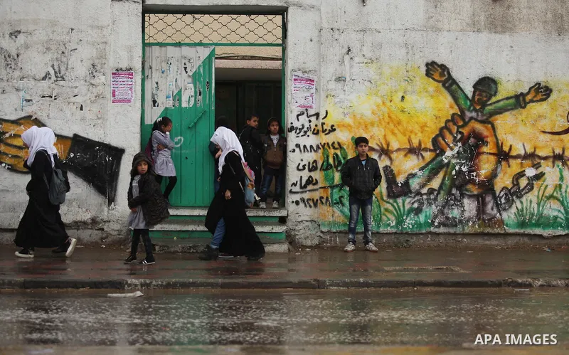Palestinian students walk in a flooded street during a rainy day, in Khan Younis in the southern Gaza strip on March 28, 2016. Photo by Ashraf Amra