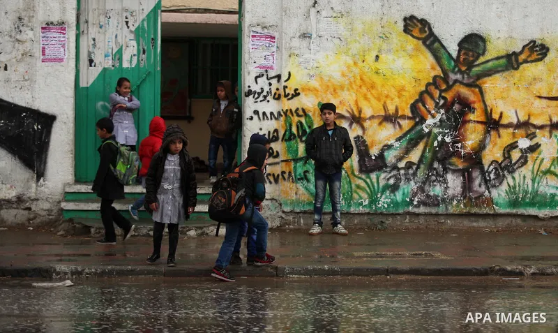 Palestinian students walk in a flooded street during a rainy day, in Khan Younis in the southern Gaza strip on March 28, 2016. Photo by Ashraf Amra