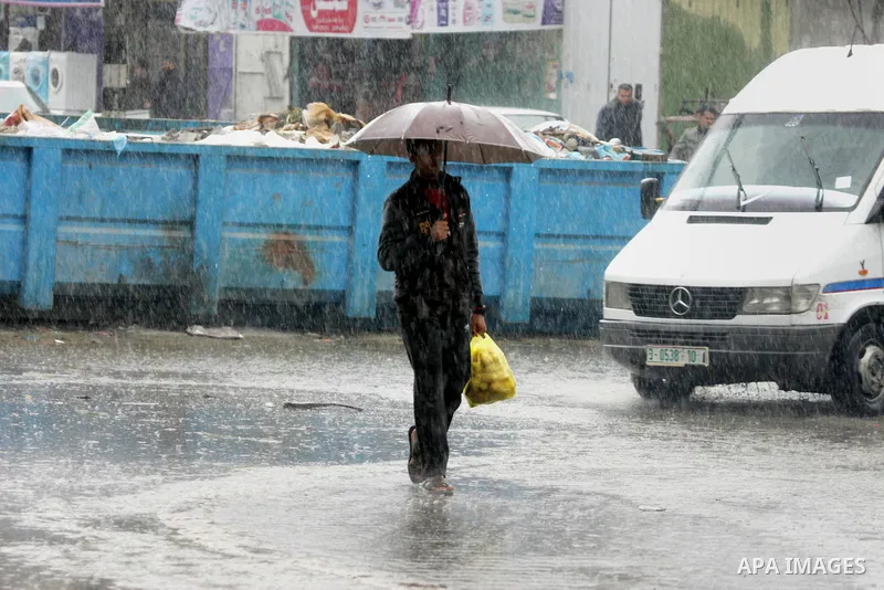 Palestinians walk in a flooded street during a rainy day, in Rafah in the southern Gaza strip on March 28, 2016. Photo by Abed Rahim Khatib