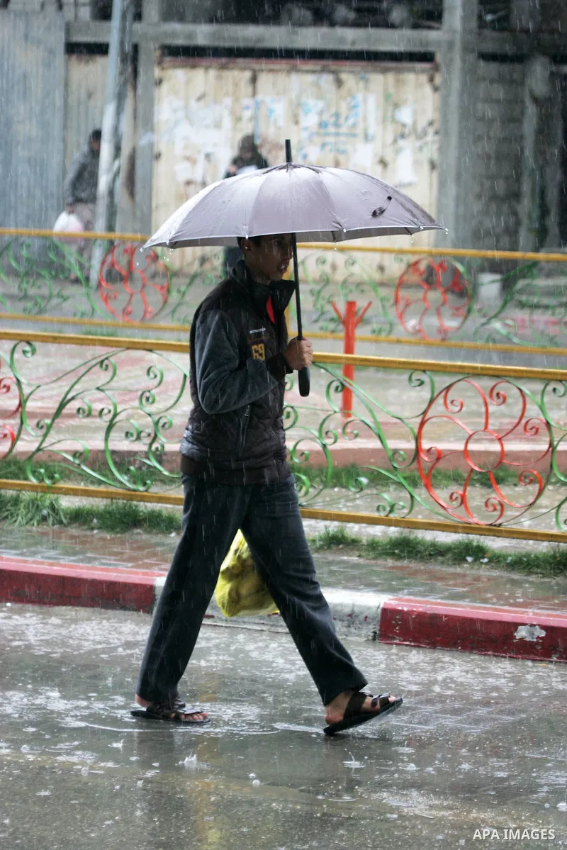 Palestinians walk in a flooded street during a rainy day, in Rafah in the southern Gaza strip on March 28, 2016. Photo by Abed Rahim Khatib