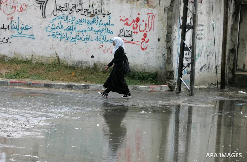 Palestinians walk in a flooded street during a rainy day, in Rafah in the southern Gaza strip on March 28, 2016. Photo by Abed Rahim Khatib