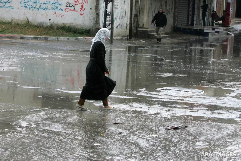 Palestinians walk in a flooded street during a rainy day, in Rafah in the southern Gaza strip on March 28, 2016. Photo by Abed Rahim Khatib