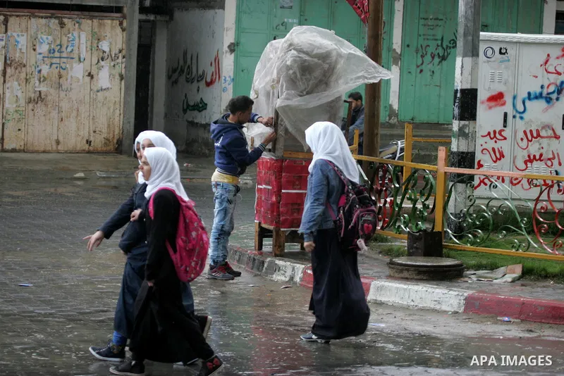 Palestinians walk in a flooded street during a rainy day, in Rafah in the southern Gaza strip on March 28, 2016. Photo by Abed Rahim Khatib