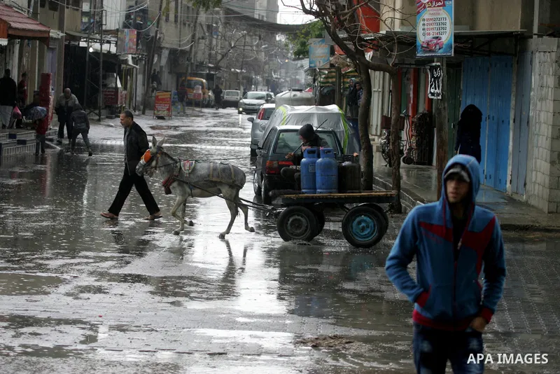Palestinians walk in a flooded street during a rainy day, in Rafah in the southern Gaza strip on March 28, 2016. Photo by Abed Rahim Khatib
