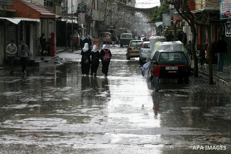 Palestinians walk in a flooded street during a rainy day, in Rafah in the southern Gaza strip on March 28, 2016. Photo by Abed Rahim Khatib