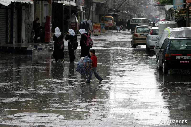 Palestinians walk in a flooded street during a rainy day, in Rafah in the southern Gaza strip on March 28, 2016. Photo by Abed Rahim Khatib