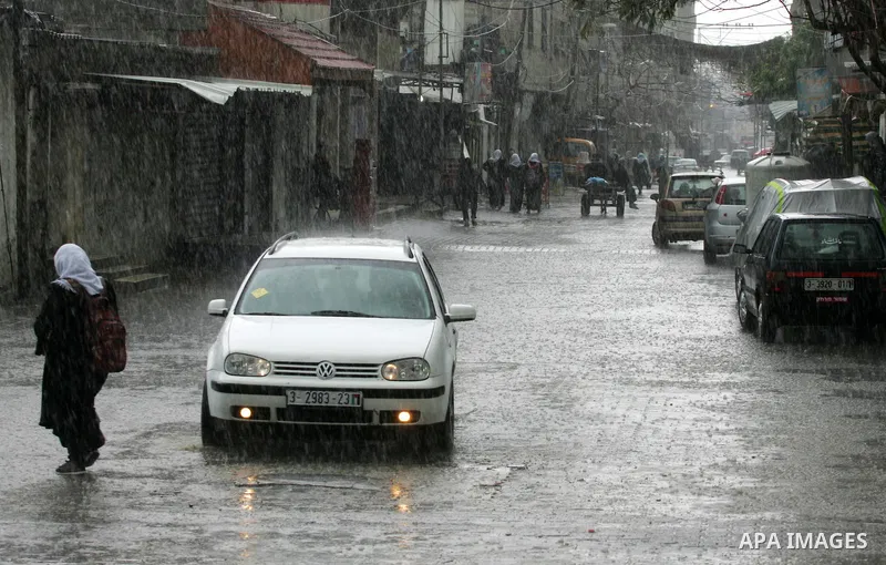 Palestinians walk in a flooded street during a rainy day, in Rafah in the southern Gaza strip on March 28, 2016. Photo by Abed Rahim Khatib