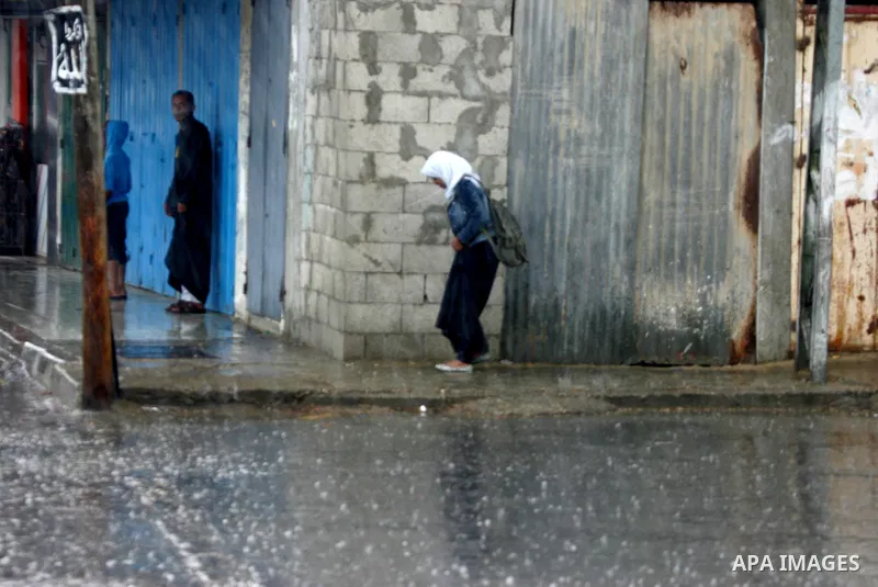 Palestinians walk in a flooded street during a rainy day, in Rafah in the southern Gaza strip on March 28, 2016. Photo by Abed Rahim Khatib
