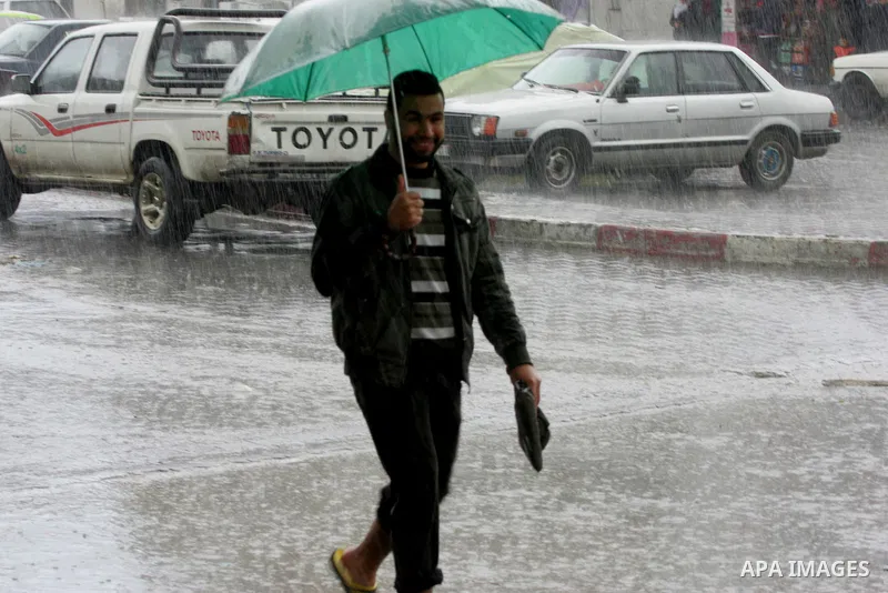 Palestinians walk in a flooded street during a rainy day, in Rafah in the southern Gaza strip on March 28, 2016. Photo by Abed Rahim Khatib