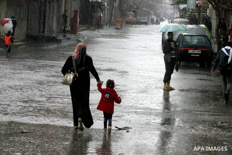 Palestinians walk in a flooded street during a rainy day, in Rafah in the southern Gaza strip on March 28, 2016. Photo by Abed Rahim Khatib