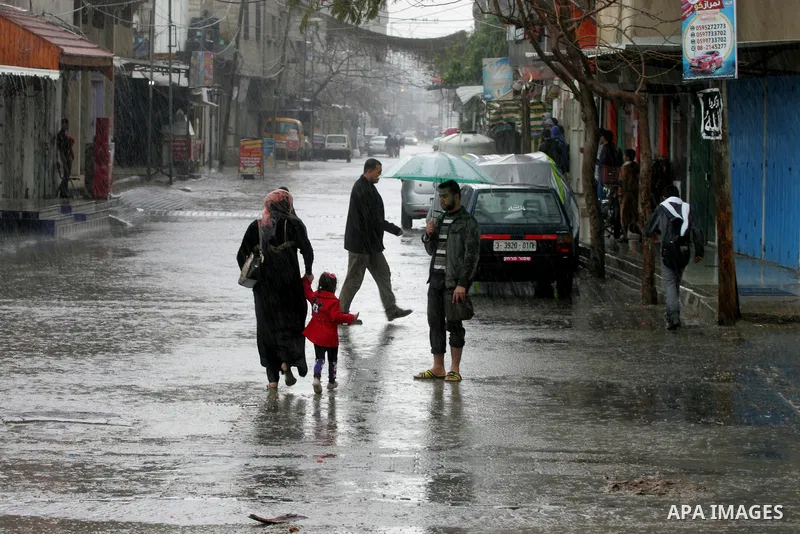 Palestinians walk in a flooded street during a rainy day, in Rafah in the southern Gaza strip on March 28, 2016. Photo by Abed Rahim Khatib