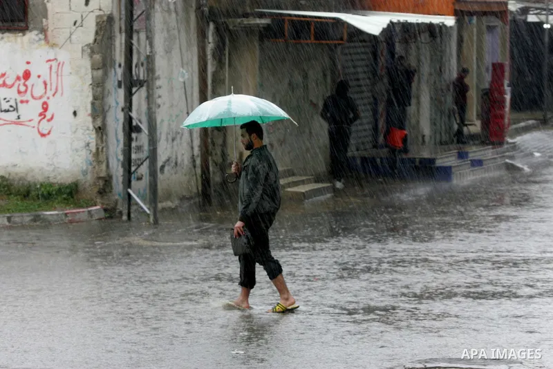 Palestinians walk in a flooded street during a rainy day, in Rafah in the southern Gaza strip on March 28, 2016. Photo by Abed Rahim Khatib