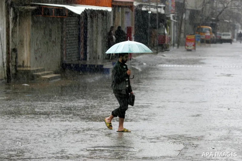 Palestinians walk in a flooded street during a rainy day, in Rafah in the southern Gaza strip on March 28, 2016. Photo by Abed Rahim Khatib
