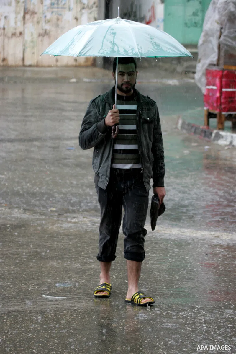 Palestinians walk in a flooded street during a rainy day, in Rafah in the southern Gaza strip on March 28, 2016. Photo by Abed Rahim Khatib
