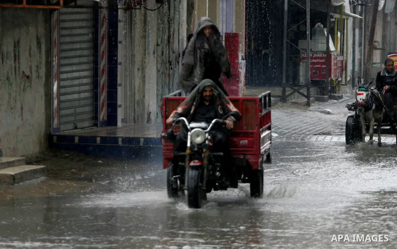 Palestinians walk in a flooded street during a rainy day, in Rafah in the southern Gaza strip on March 28, 2016. Photo by Abed Rahim Khatib