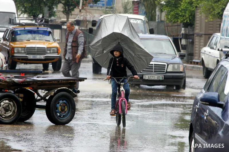 Palestinians walk in a flooded street during a rainy day, in Rafah in the southern Gaza strip on March 28, 2016. Photo by Abed Rahim Khatib